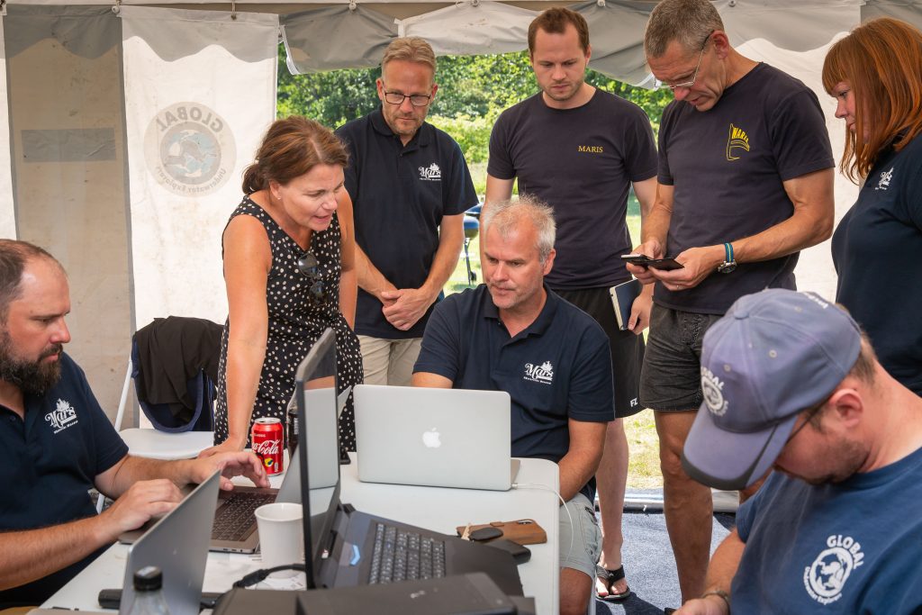 A group of researchers and divers on the 2018 Mars Project look at the data collected on a computer. 